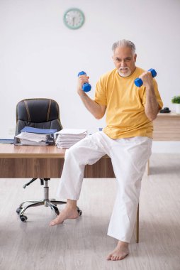 Ofiste spor egzersizleri yapan eski bir işadamı.