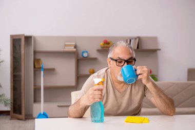 Yaşlı adam evde ev işi yapıyor.