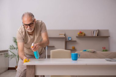 Yaşlı adam evde ev işi yapıyor.