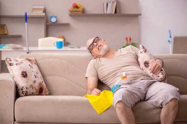 Yaşlı adam evde ev işi yapıyor.