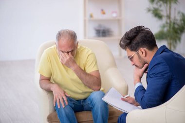 Yaşlı adam genç erkek psikoterapisti ziyaret ediyor.