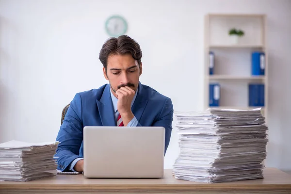 Joven empleado masculino y demasiado trabajo en la oficina — Foto de Stock