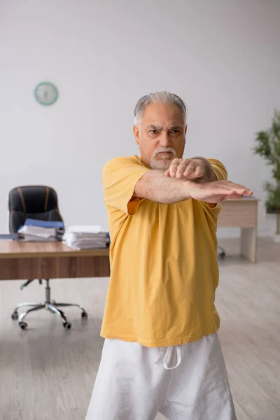 Old businessman employee doing sport exercises in the office — Stock Photo, Image