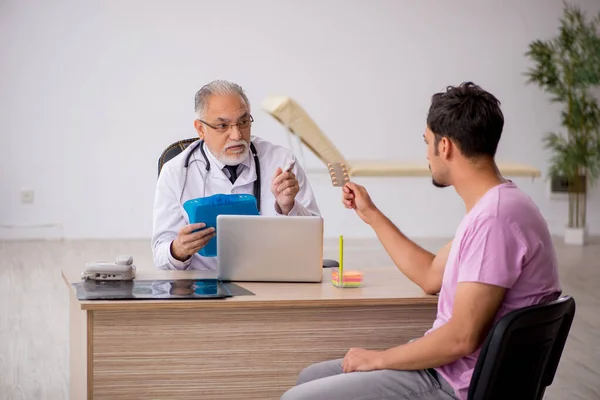 Fiatal férfi beteg látogató idős férfi orvos — Stock Fotó