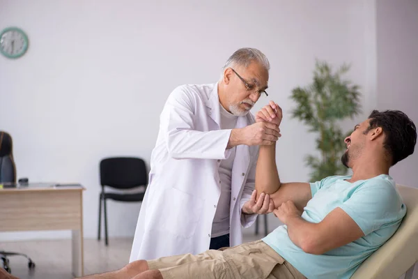 Joven paciente masculino visitando viejo médico masculino — Foto de Stock