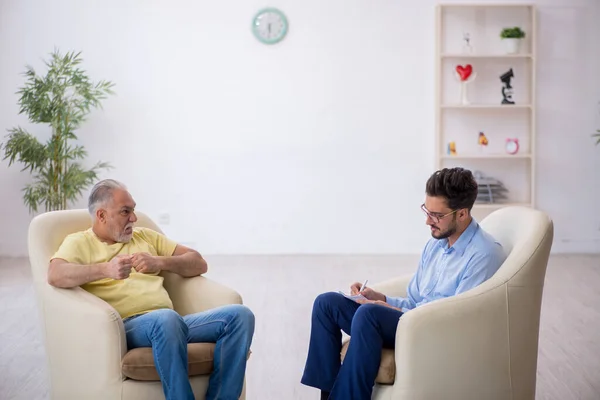 Velho visitando jovem psicoterapeuta masculino — Fotografia de Stock