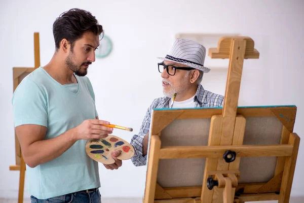 Old painter teaching young student at studio — Stock Photo, Image