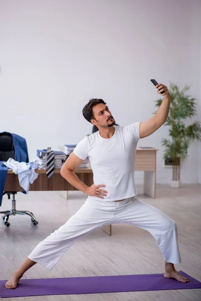Joven empleado masculino haciendo ejercicios deportivos en la oficina — Foto de Stock
