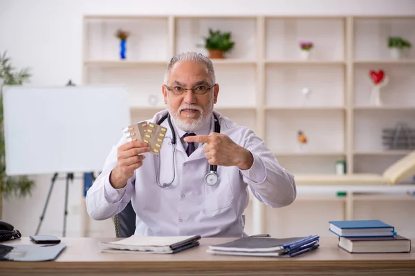 Yaşlı erkek doktor hastanede hap öneriyor. — Stok fotoğraf