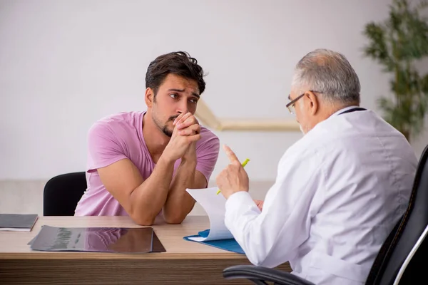 Ung manlig patient besöker gamla manliga läkare — Stockfoto