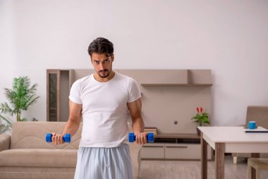 Genç adam evde spor yapıyor.