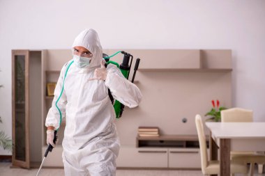 Genç erkek müteahhit evde haşere kontrolü yapıyor.