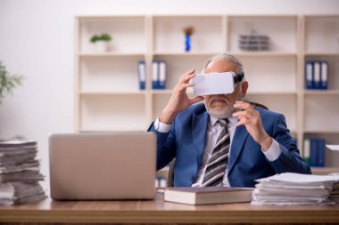 Ofiste sanal gözlük takan yaşlı bir erkek çalışan.