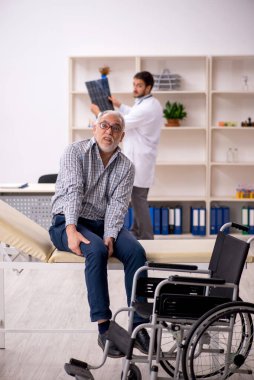 Yaşlı adam genç erkek doktor radyolojisti ziyaret ediyor.