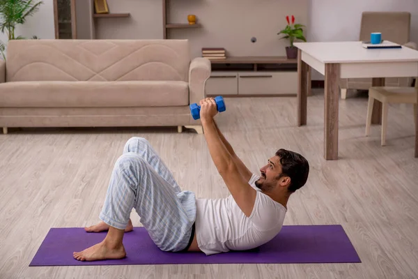 Jovem fazendo exercícios esportivos em casa — Fotografia de Stock