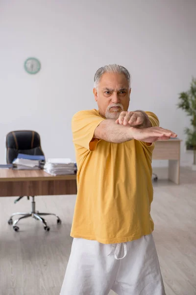 Oude zakenman werknemer doet sport oefeningen in het kantoor — Stockfoto