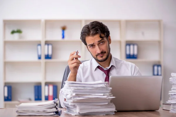 Jovem funcionário masculino e muito trabalho no escritório — Fotografia de Stock