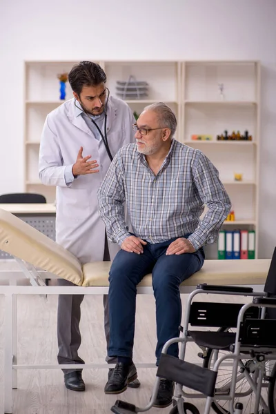Tekerlekli sandalyedeki yaşlı adam genç erkek doktoru ziyaret ediyor.
