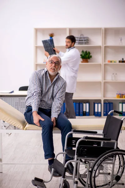 Yaşlı adam genç erkek doktor radyolojisti ziyaret ediyor.