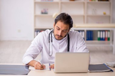 Klinikte çalışan genç erkek doktor.