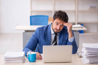 Genç bir erkek çalışan ve ofiste çok fazla iş var.