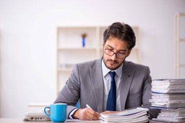 Genç bir erkek çalışan ve ofiste çok fazla iş var.