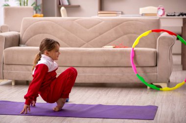 Küçük kız evde spor yapıyor.