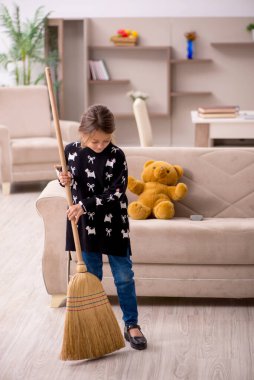 Küçük kız evde ev işi yapıyor.