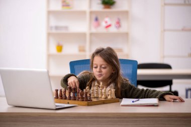 Küçük kız evde satranç oynuyor.