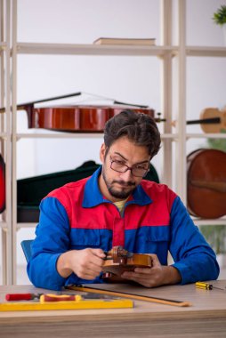 Genç adam atölyede müzik aletlerini tamir ediyor.