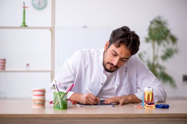 Klinikte çalışan genç erkek dişçi.