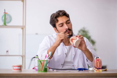 Klinikte çalışan genç erkek dişçi.