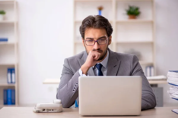 Joven empleado masculino y demasiado trabajo en la oficina — Foto de Stock