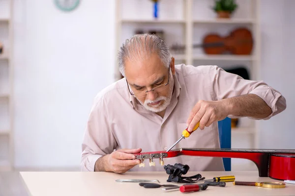 Viejo reparador masculino reparando instrumentos musicales en el taller — Foto de Stock