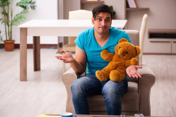 Giovane seduto con orso giocattolo a casa — Foto Stock