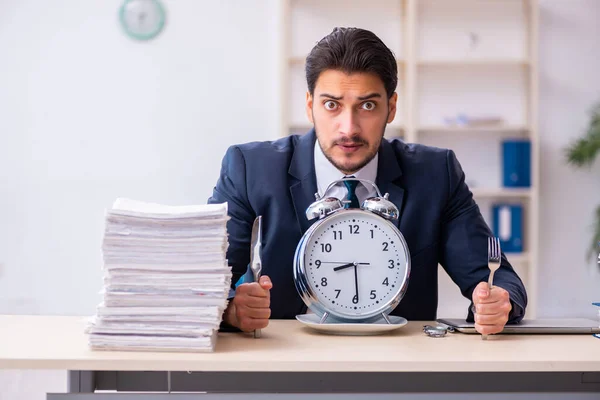 Joven empleado de negocios comiendo despertador-reloj — Foto de Stock