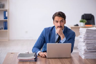 Ofisteki aşırı işten memnun olmayan genç bir erkek işçi.