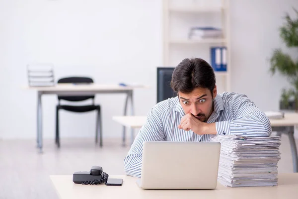 Jovem funcionário masculino e muito trabalho no escritório — Fotografia de Stock