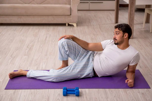 Jovem fazendo exercícios esportivos em casa — Fotografia de Stock