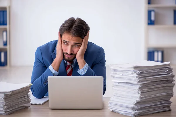 Ung manlig anställd och för mycket arbete på kontoret — Stockfoto