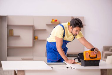 Genç erkek marangoz evdeki masayı onarıyor.