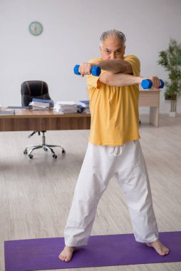 Ofiste spor egzersizleri yapan eski bir işadamı.