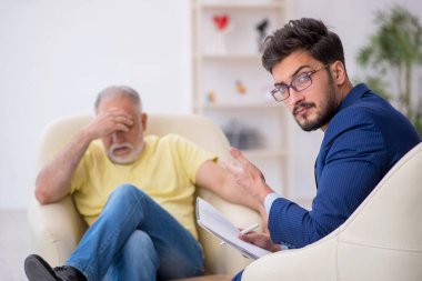 Yaşlı adam genç erkek psikoterapisti ziyaret ediyor.