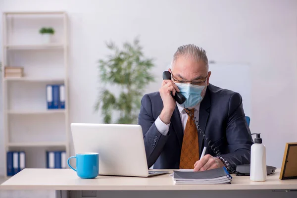 Gammal manlig anställd som arbetar på kontoret under pandemin — Stockfoto