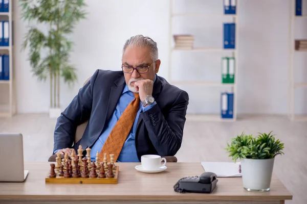 Old businessman playing chess at workplace — Stock Photo, Image