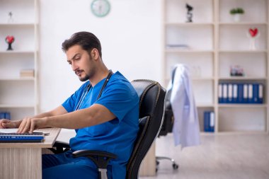 Klinikte çalışan genç erkek doktor.