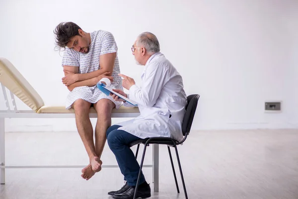 Oude mannelijke dokter psychiater onderzoekt jonge mannelijke patiënt — Stockfoto
