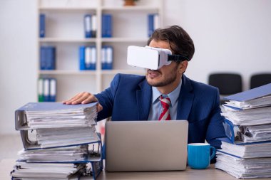 Genç erkek çalışan, iş yerinde sanal gözlüklerin keyfini çıkarıyor.