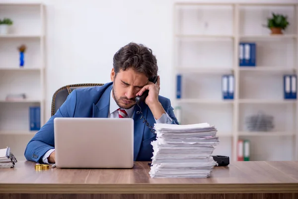 Ung manlig anställd och för mycket arbete på kontoret — Stockfoto