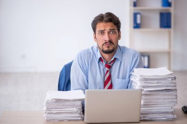 Genç bir erkek çalışan ve ofiste çok fazla iş var.